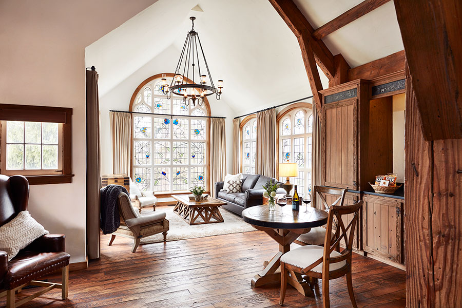 Carriage House accommodations at Big Cedar Lodge. The photo includes a photo of a sitting area, table and chairs, decorative chandelier and large windows.