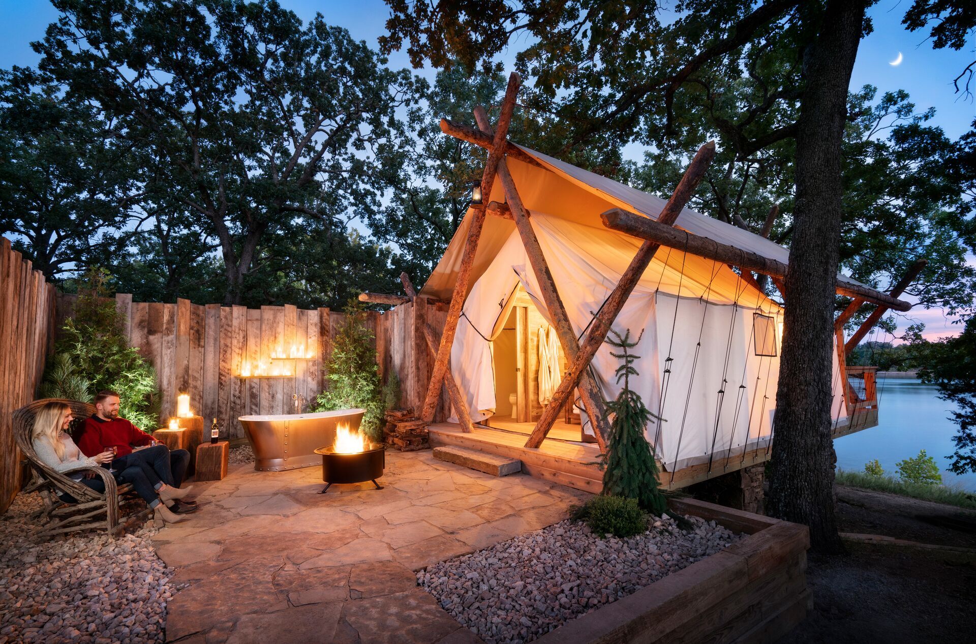 couple enjoys fire outside a glamping tent at twilight