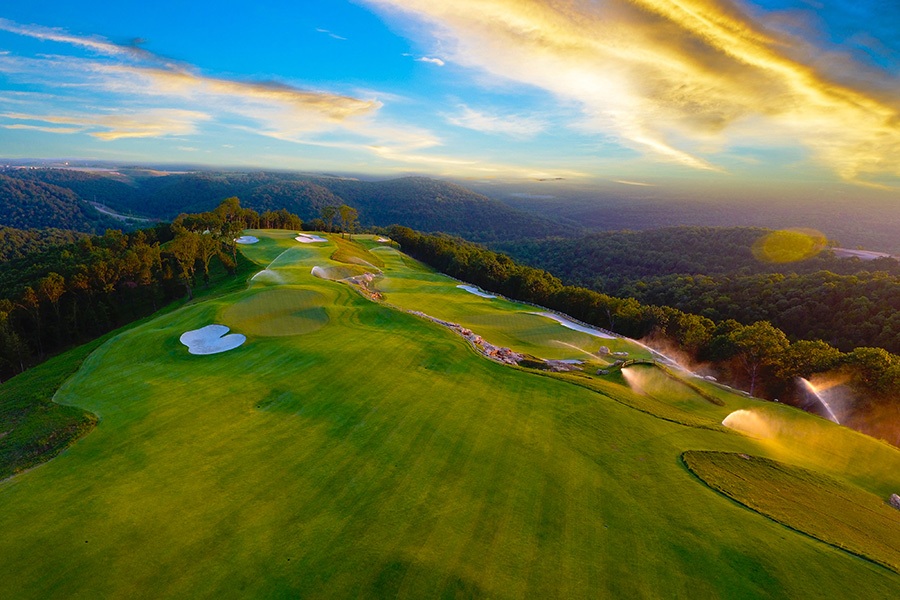 a long fairway reaches into the sky where a yellow sunset waits