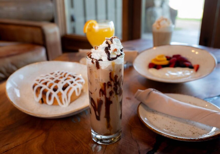 a cinnamon roll, coffee drink, fruit and yogurt