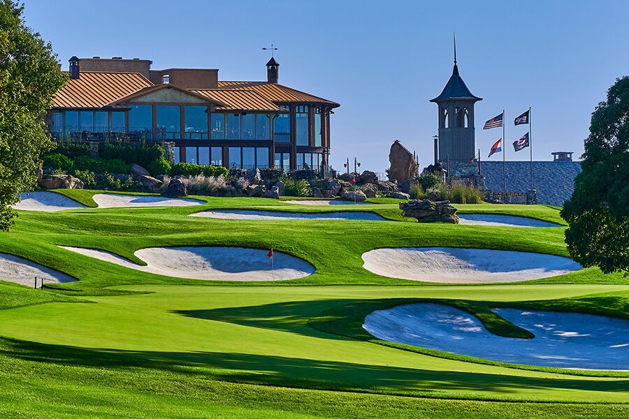 a golf course and several sand bunkers sit at the foot of a lodge and chapel