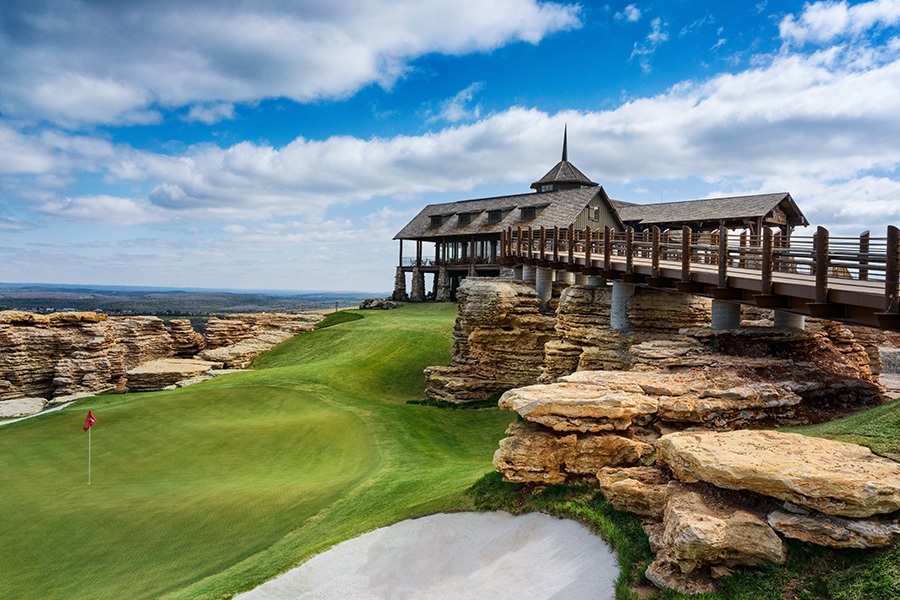 mountain top clubhouse sits on the edge of a cliff next to a putting green