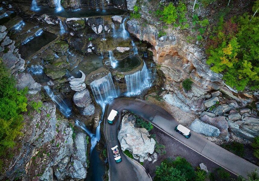 One of the picturesque waterfalls on the Lost Canyon Cave & Nature Trail with several golf carts driving passed it.