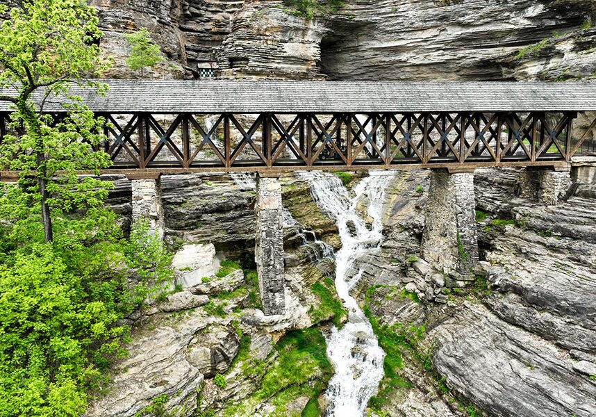 The Amish Bridge on the Lost Canyon Cave & Nature Trail at Top of the Rock with a stream flowing under it.