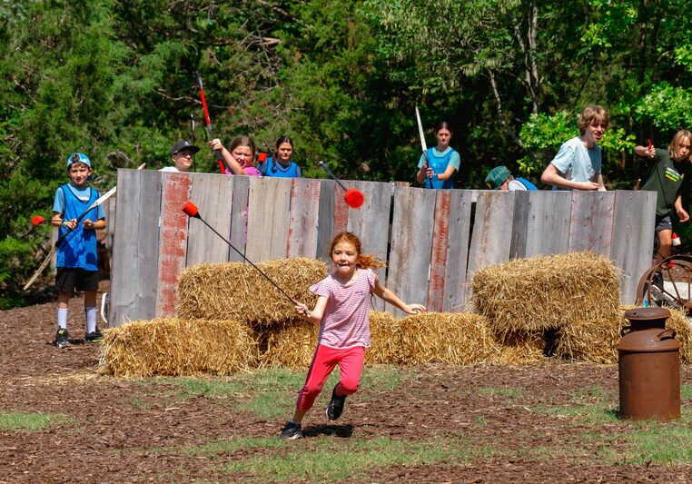 Little girl running and dodging padded arrows