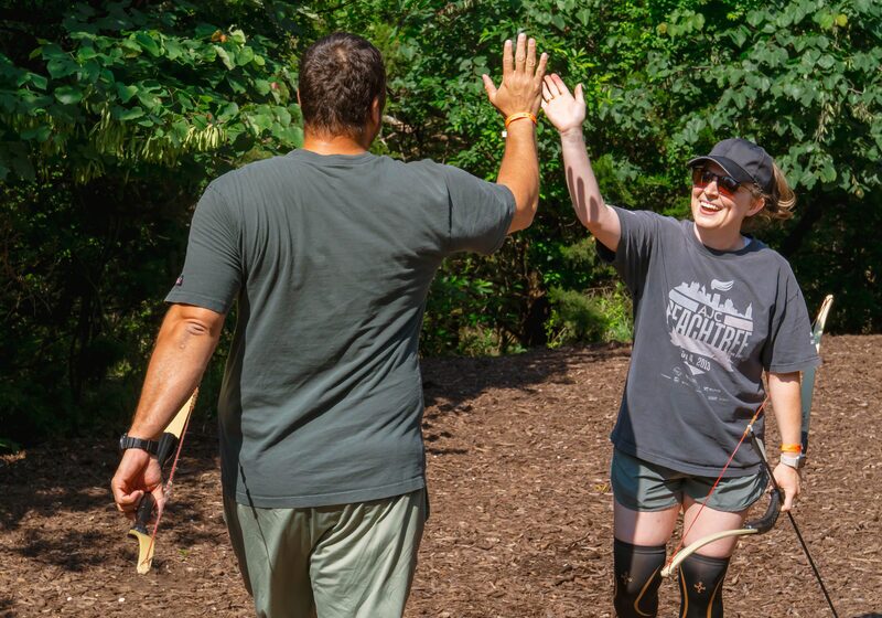 man and woman smile and give each other a high five after a round Archery Tag