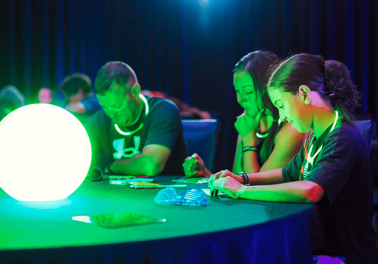 Group playing bingo around a glowing green light