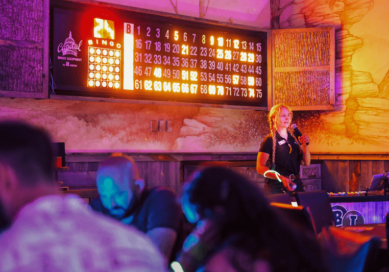 announcer reading off bingo numbers with glowing orange light up bingo display behind her