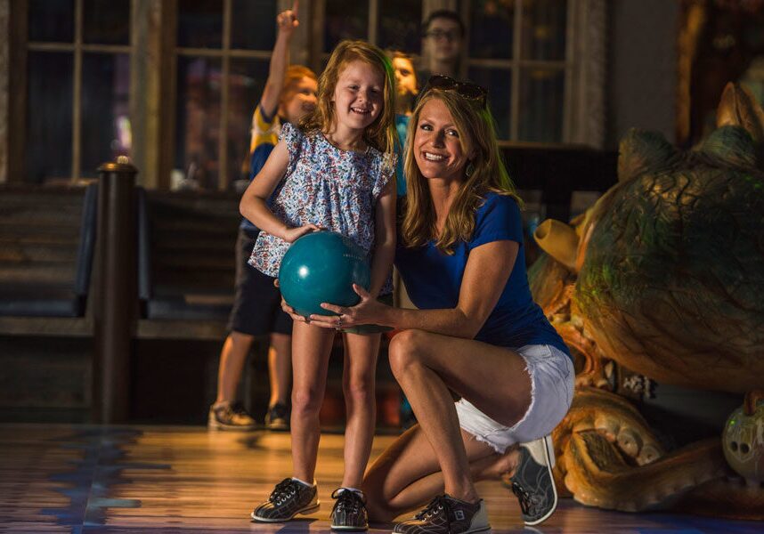 Mom helping daughter bowl at Fun Mountain underwater-themed bowling alley at Big Cedar