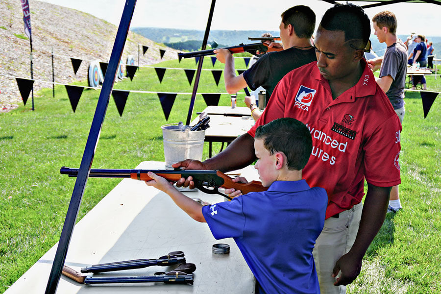 Young boy being taught how to shoot an air riffle at the Air Riffle Bullseye event at Big Cedar