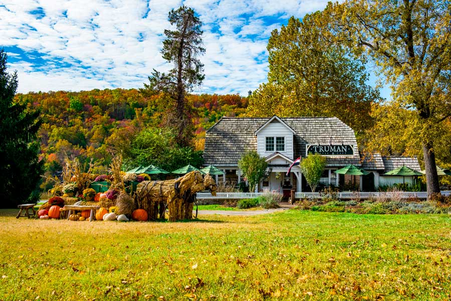 Fall decor in with straw horse, carriage, and pumpkins in front of Truman Café & Custard