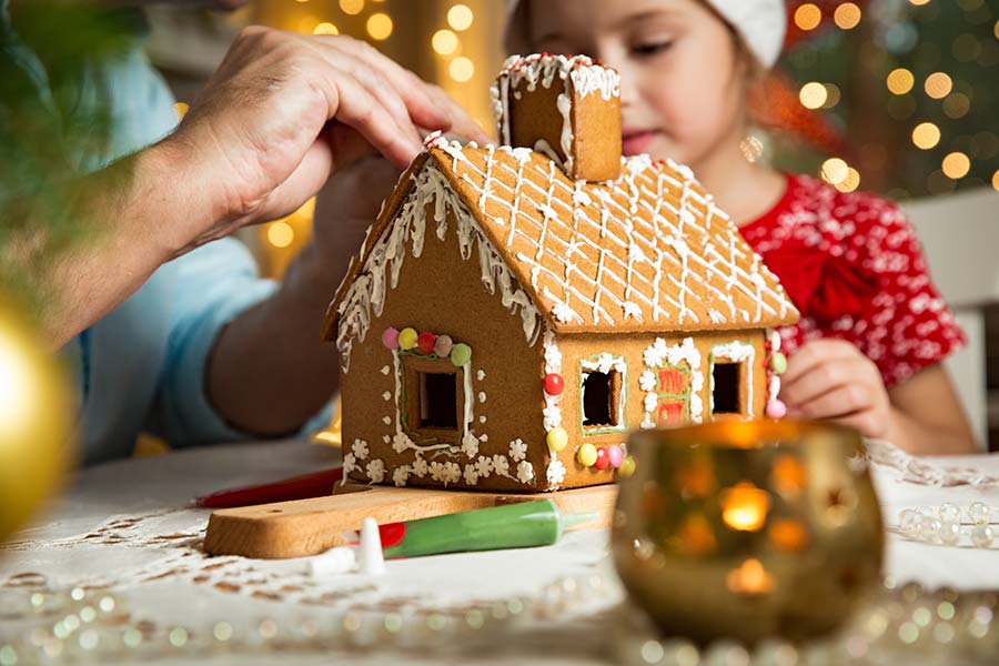 Father and daughter building gingerbread house