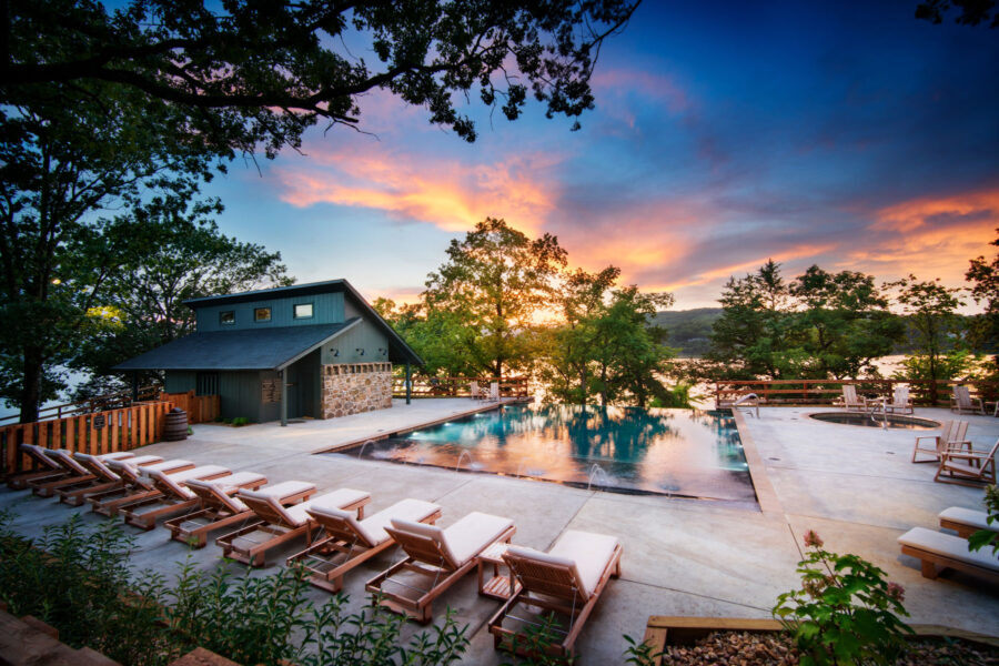 Camp Long Creek swimming pool lined with reclining chairs, vivid sunset and lake in the background