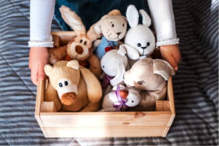 Child holding a box of stuffed animals