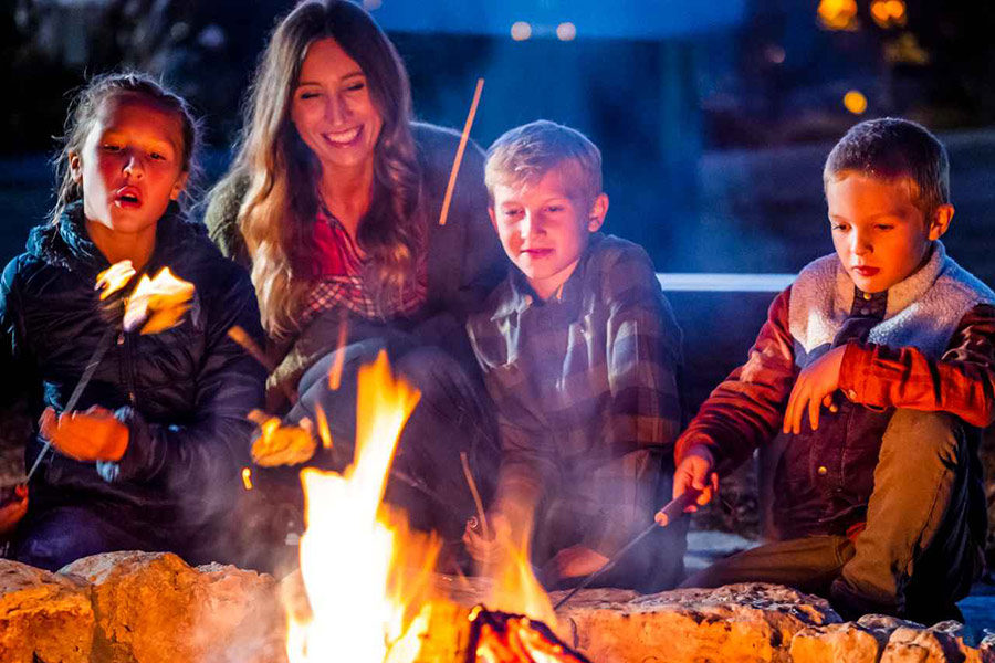 Family sitting near campfire roasting marshmellows