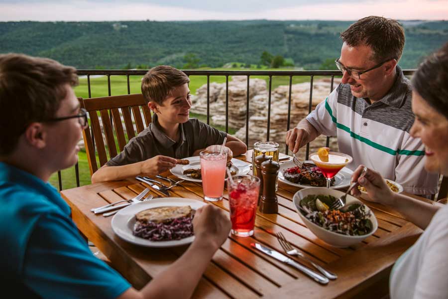 Family of four enjoying a delicious meal overlooking the golf course at Mountain Top Grill