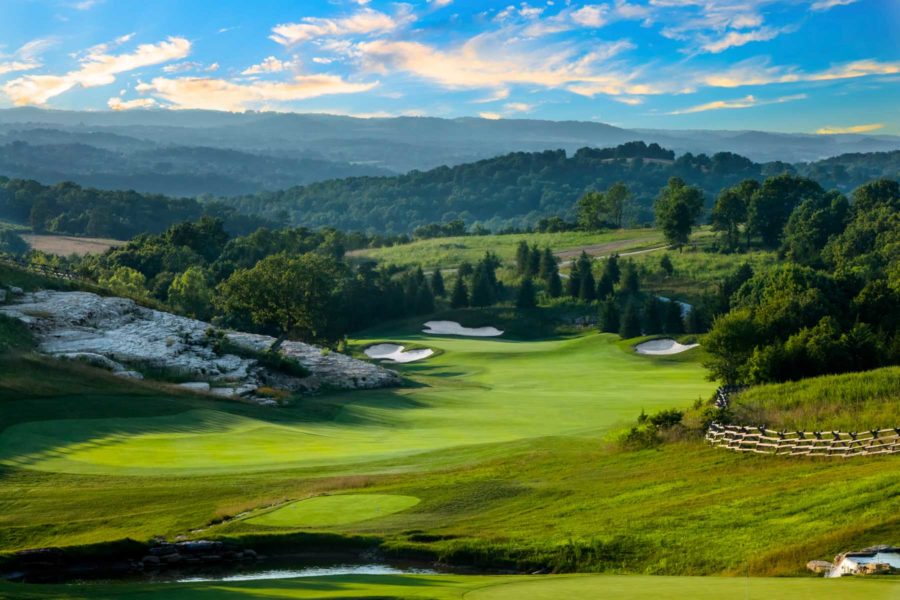 Vivid blue sky with a few clouds over Buffalo Ridge hole #2. Tree-covered rolling hills meet the sky in the background