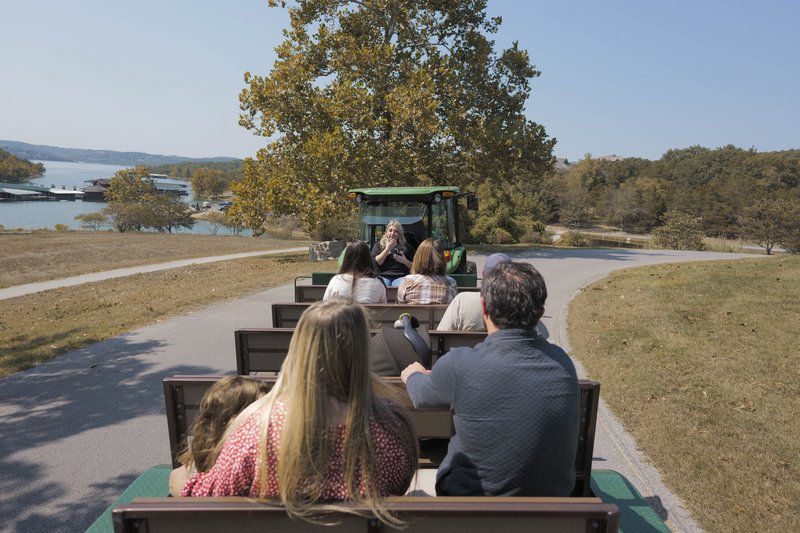 A group rides an open air tram in autumn pulled by a John Deere Tractor