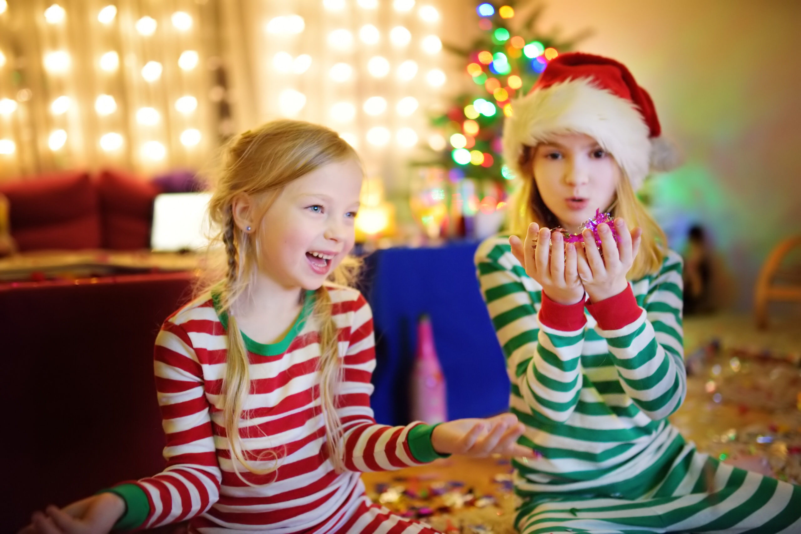 Two adorable sisters celebrating New Years eve in beautifully decorated room at home.