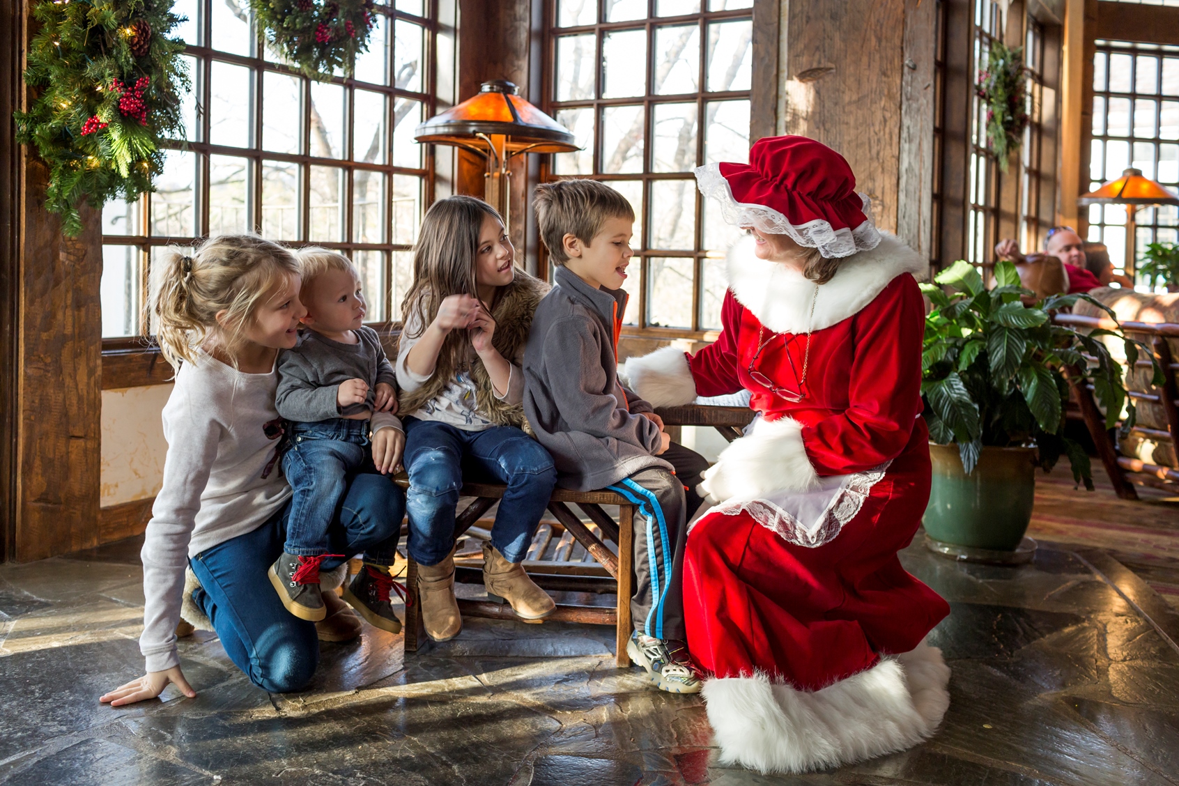 Mrs. Claus is reading to a group of eagerly listening children in the resort lobby