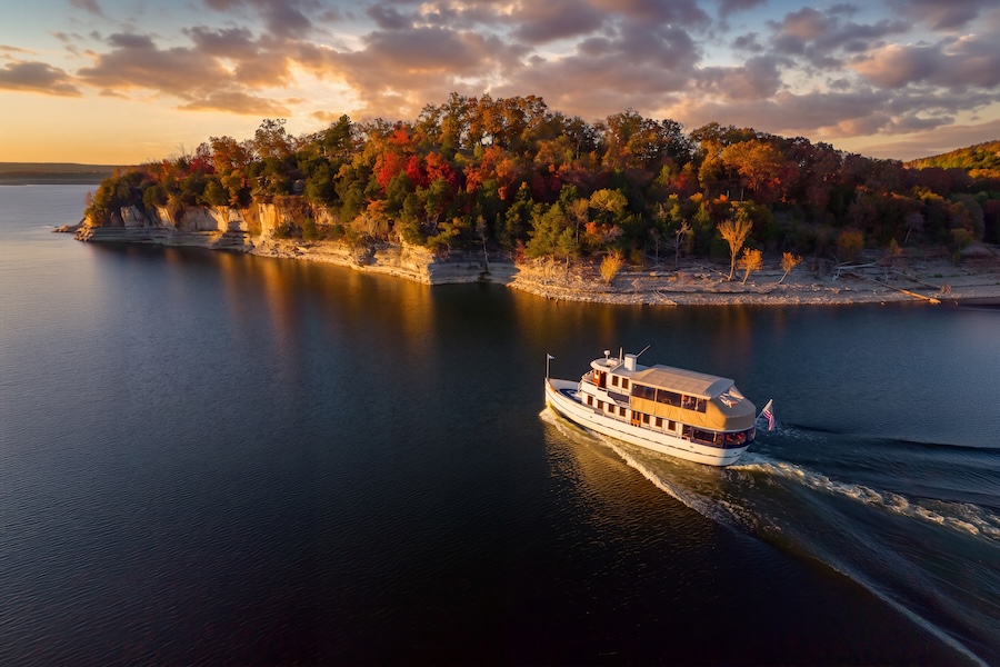 Lady Liberty vintage luxury tour yacht at sunset on the lack by limestone cliffs topped with red autumn forest