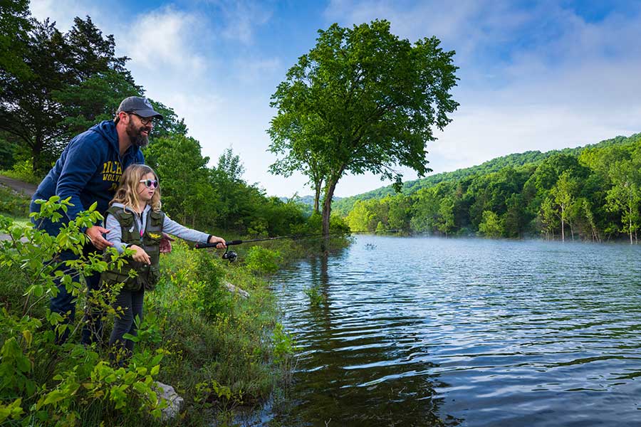 A father and daughter fish together of the shores of Table Rock Lake