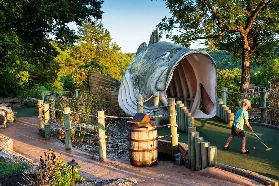 A young boy playing on the Big Bass Mini Golf course