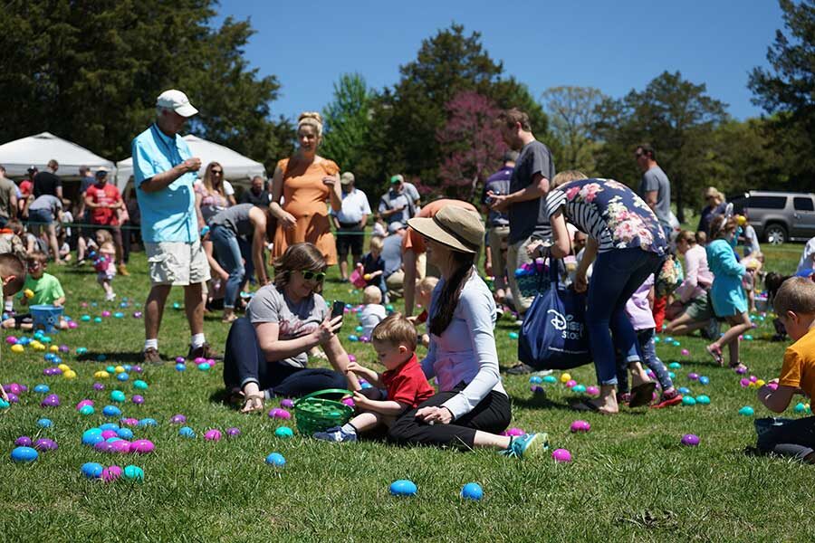family celebrates easter surrounded by eggs in a field