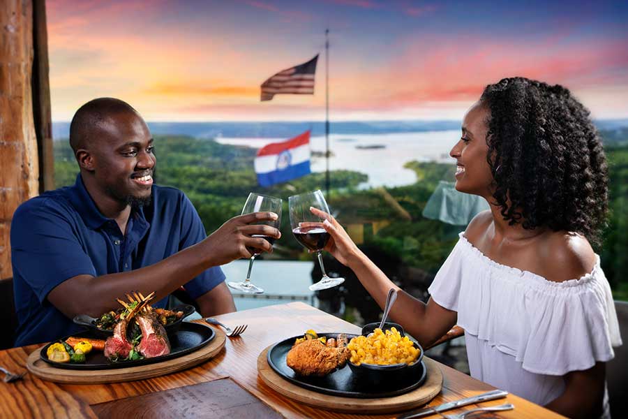 A couple makes a toast over dinner at Osage Restaurant, just as the sun dips below the horizon