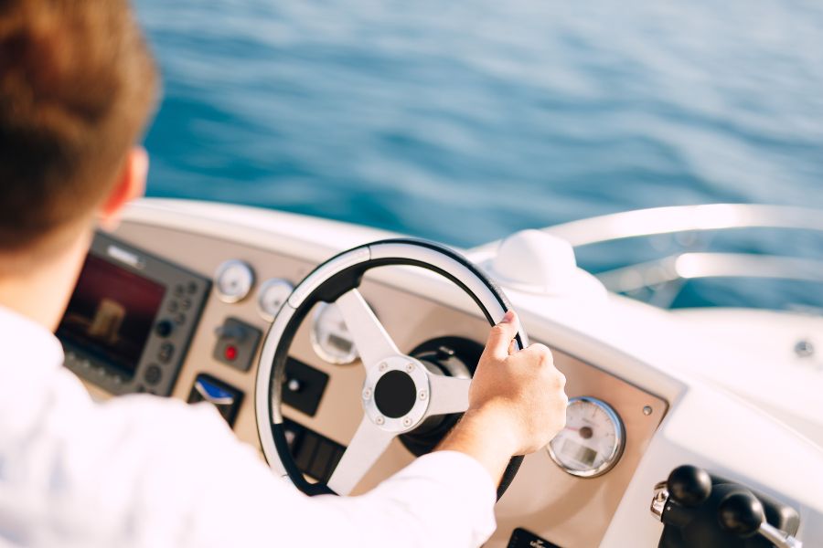 A boat captain guides her motorboat through calm blue waters.