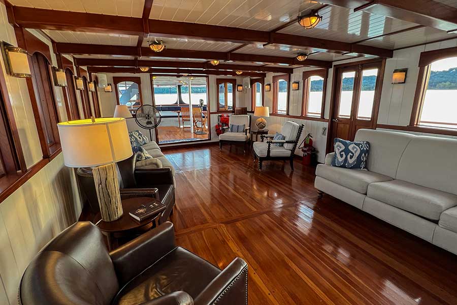 A luxurious lounge on board the Lady Liberty Luxury, including vintage furniture and polished wood floors.