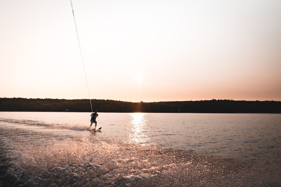 A person wakeboards on Table Rock Lake at sunset.