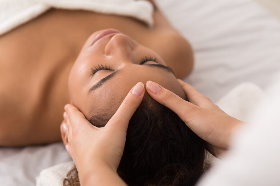 Woman enjoying anti aging facial massage in spa salon African-american woman enjoying anti aging facial massage in spa salon