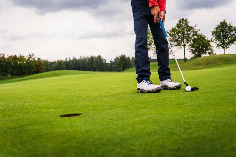 golf hit on green Boy golf player putting golf ball onto green
