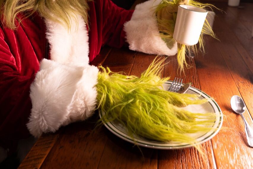 The grinch with a plate and coffee cup