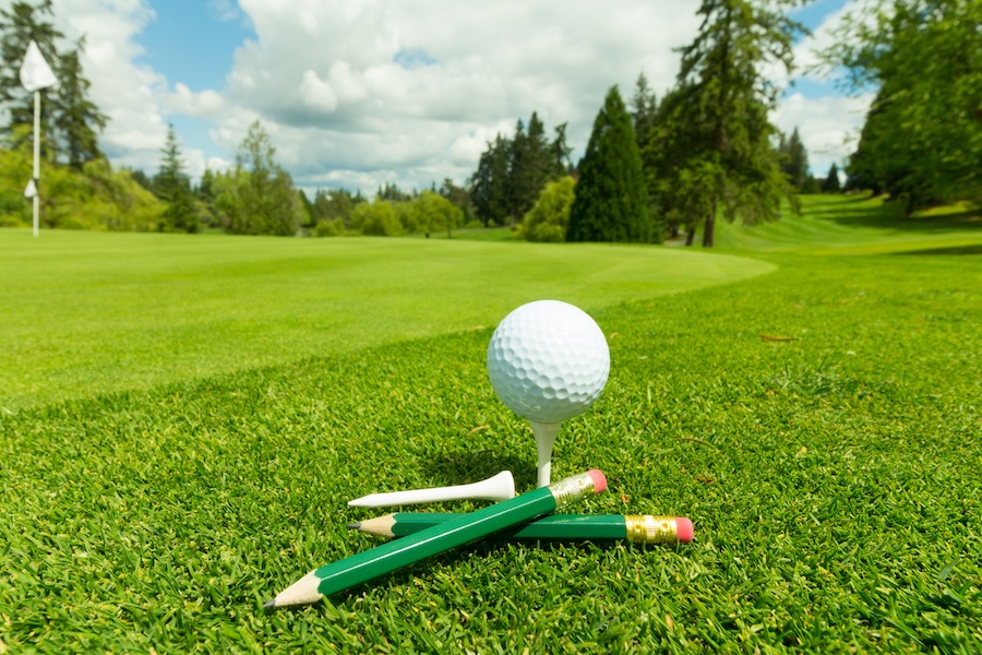 Golf Ball on tee with a stack of pencils next to it.