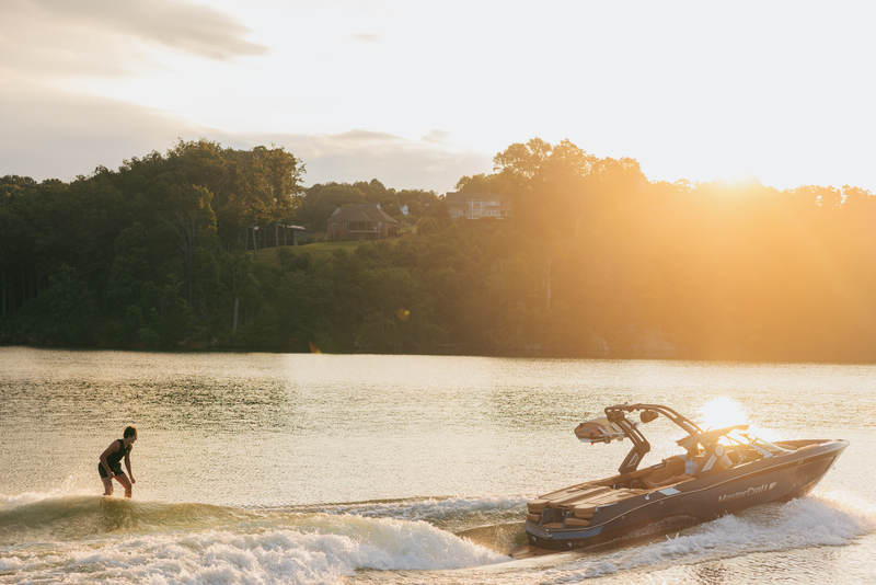 Wake Board lesson taking place at sunset on a lake next to a forested coastline