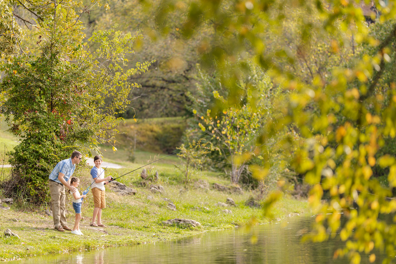 Father fishing with son and young daughter on the bank of the lake