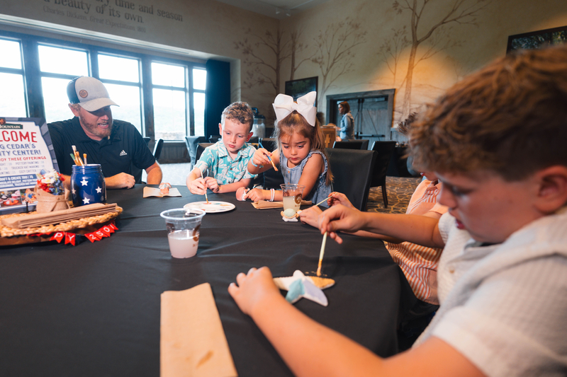Family paints small clay art pieces at a round table