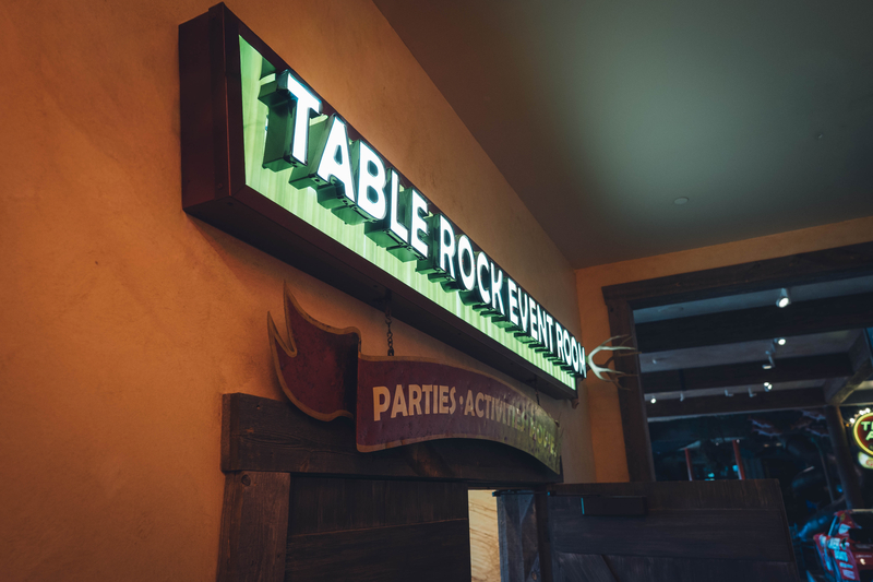 A light up sign above a doorway that says Table Rock Event Room in white letter on a green background