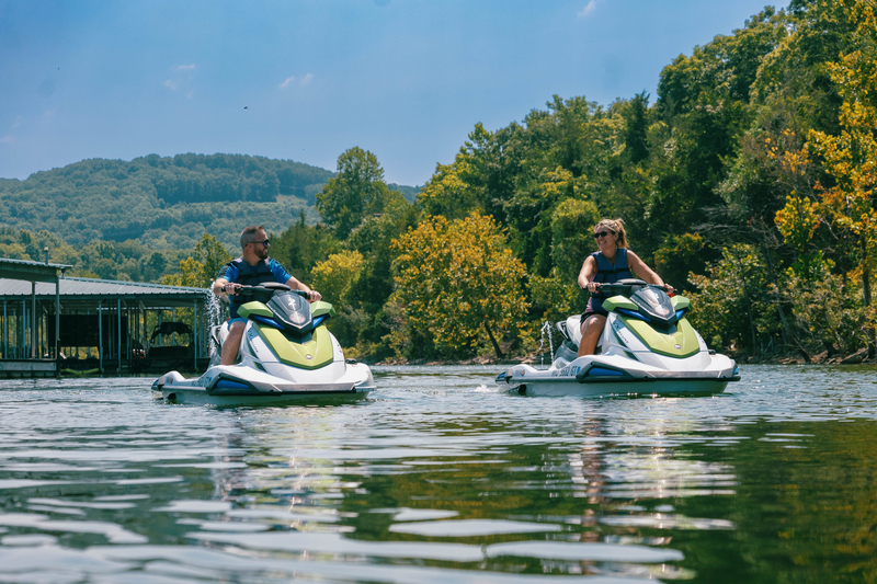 A couple rides a pair of jet skis on the lake