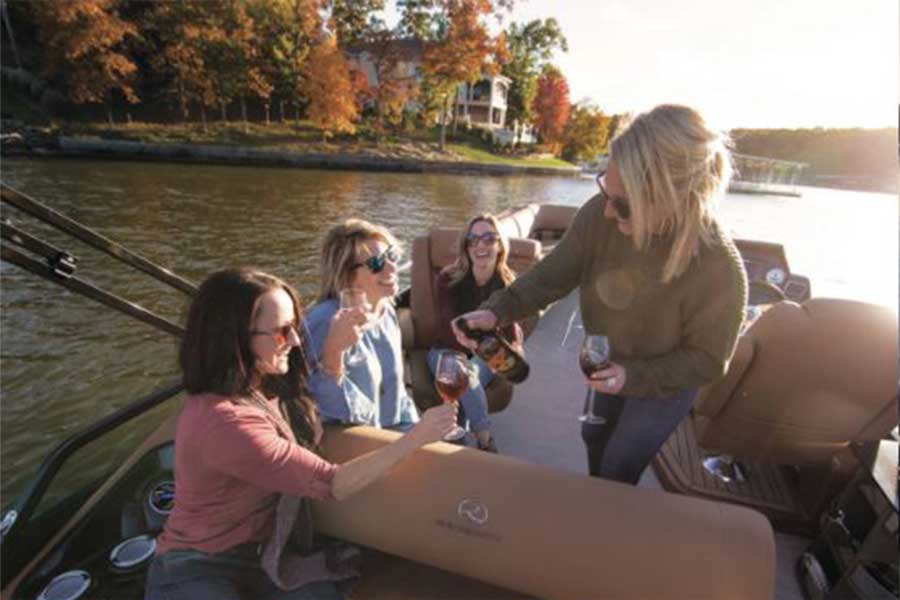 A group of women enjoy wine on a luxury pontoon in the fall on Table Rock Lake