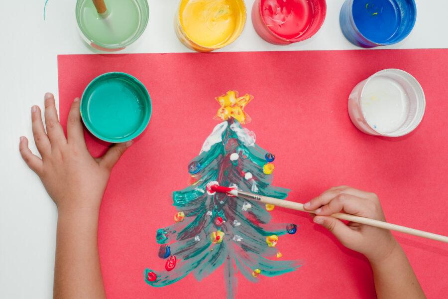 A child paints and image of a colorful Christmas tree