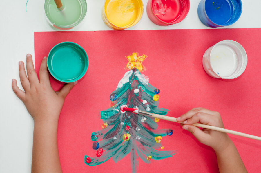 A child paints and image of a colorful Christmas tree