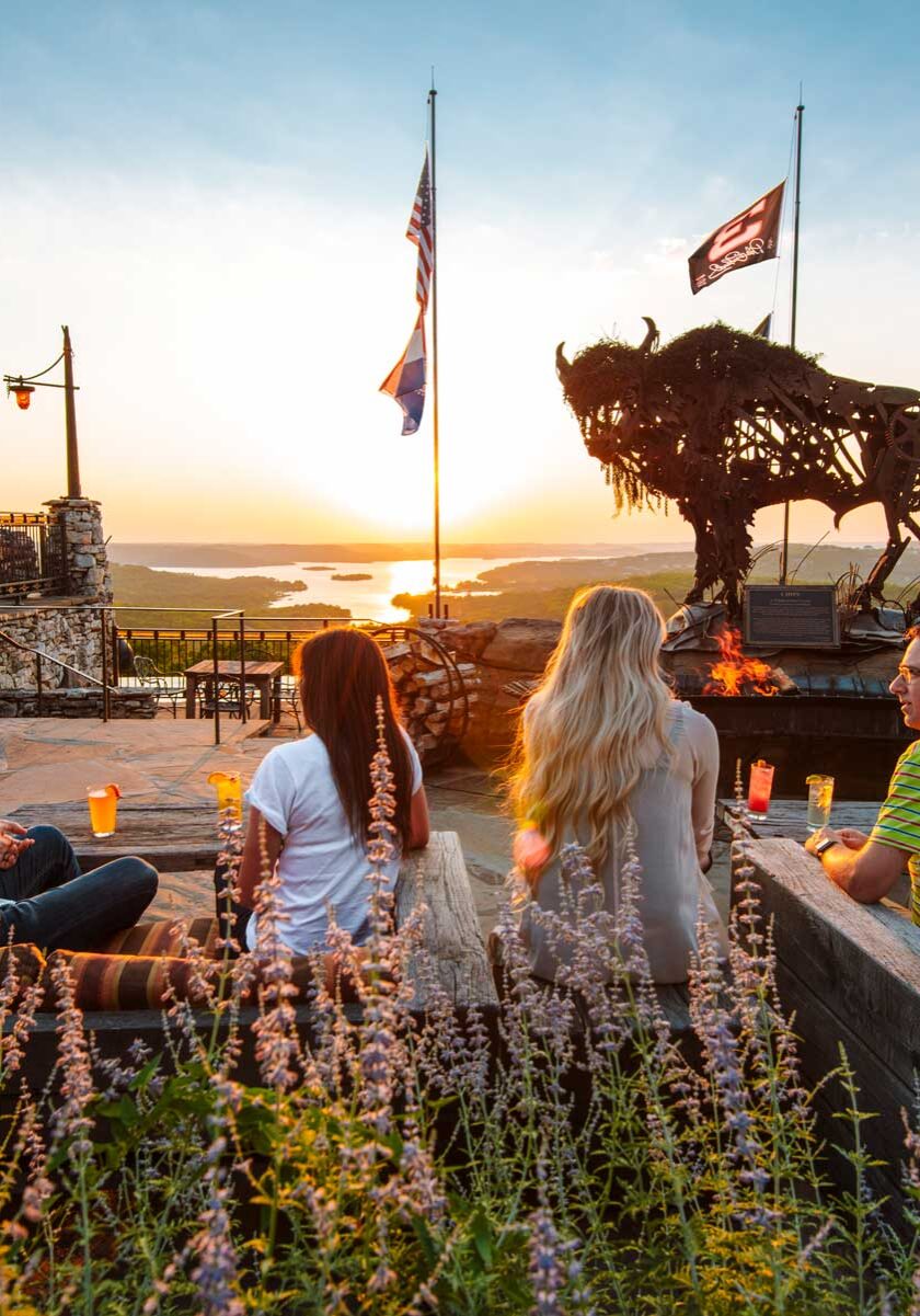 2 couples dining on the Buffalo Bar patio with the sun sinking below the horizon