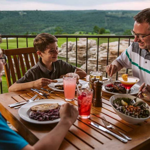 Family of four enjoying a delicious meal overlooking the golf course at Mountain Top Grill