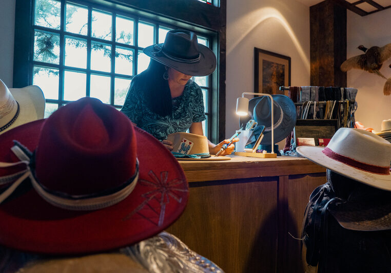 Woman using a hot pyrography pen to burn a design into a leather hat