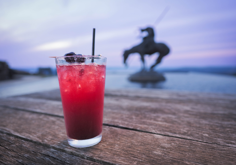 Colorful drink at sunset with statue in background