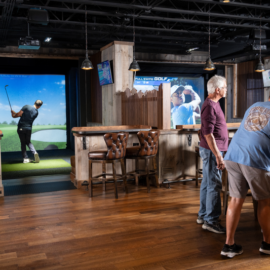Man plays virtual golf in a simulator bay